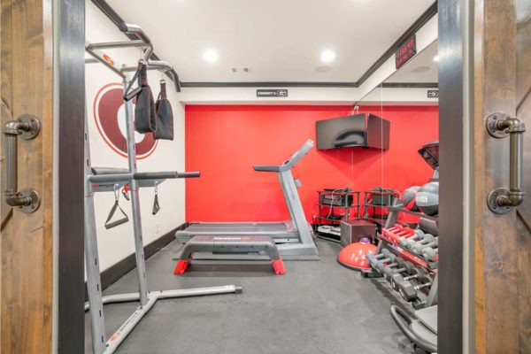 Basement gym with mirrored wall, and rubber flooring.