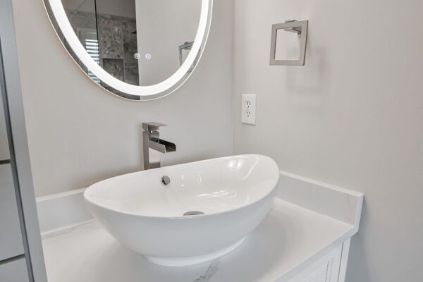 Quartz countertops, and white vessel sink are stunning in the renovated master bath.