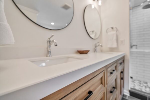 White quartz countertops, and natural wood cabinetry looks awesome in this master bath renovation.