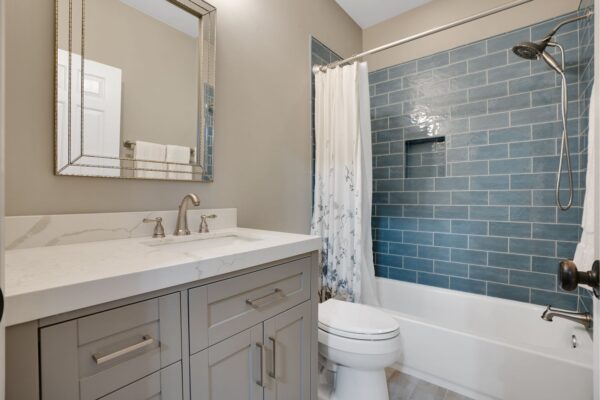 Newly remodeled bathroom with quartz countertops, and subway tile tub surround.